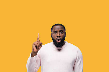 Handsome african american man points for finger on copy space for your advertising, his face is...