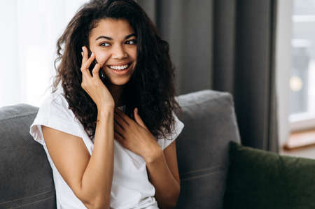 Pretty african american woman use smartphone, talking with friends or family. Young attractive...