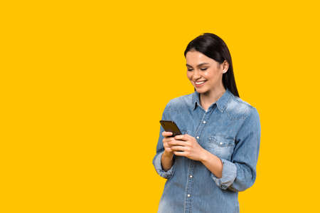 Chatting online. Caucasian satisfied girl texting online using her smartphone, typing message to...