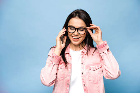 Young beautiful caucasian brunette woman talking on mobile phone with friends, family or boyfriend,...