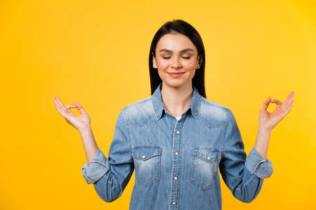 Photo of a pretty caucasian positive young woman with closed eyes, meditates and smiles on isolated...