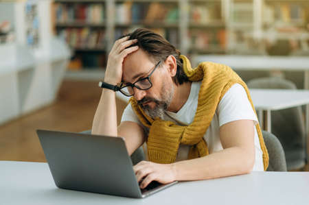 Frustrated male manager is sitting at the work desk, sed about failed project. Middle aged...