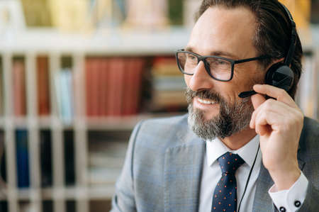 Close-up portrait of satisfied helpful mature male call center operator, employee of support center...