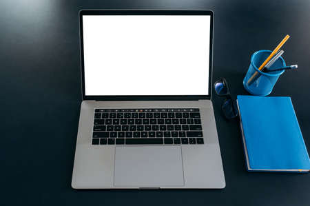 Close-up photo of a workplace, a laptop with a empty white screen, a notepad and a stationery. Copy spaceの写真素材
