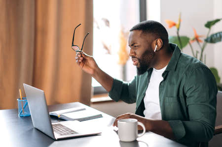 Dissatisfied confused multiracial african american male freelancer or manager, discouraged looks at...