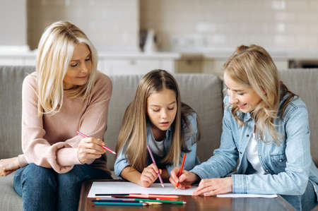 Fun and useful leisure. Caucasian happy grandmother daughter and granddaughter spend time at home...