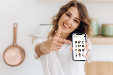 Kyiv, Ukraine - February 28, 2021. A defocused girl holds a smartphone with the icon of a Clubhouse app on the iPhone screen and points finger at it. App for a voice communication of peopleのeditorial素材