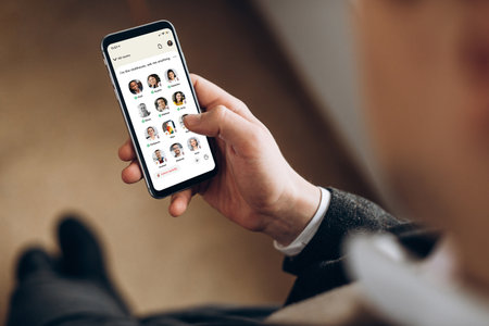 Kyiv, Ukraine - February 28, 2021. Top view of a male hand holds smartphone with the Clubhouse app on the screen, app for audio communication only, of diverse people around the worldのeditorial素材