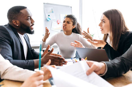 Angry business partners sitting in office on negotiations, cant coming to agreement. Multiethnic colleagues arguing, blame each other, failed a startup, unsuccess conceptの写真素材