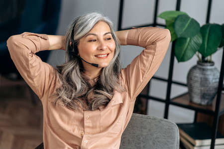 Joyful successful influential senior gray-haired asian business woman, top manager, freelancer,...