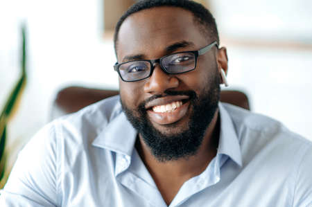 Close-up portrait of a handsome friendly intelligent African American man in formal blue shirt and...