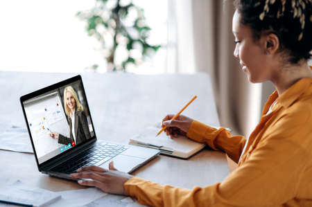 Distance learning by video conference. African American female student learning at home using a...