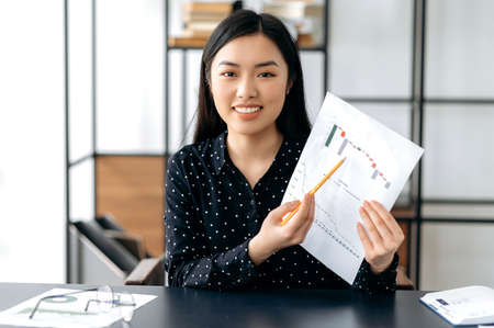 Successful attractive smart confident asian business woman, financial coach or top manager sitting...