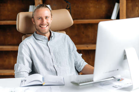 Portrait of happy successful smart young adult Caucasian manager, businessman or CEO with beard,...