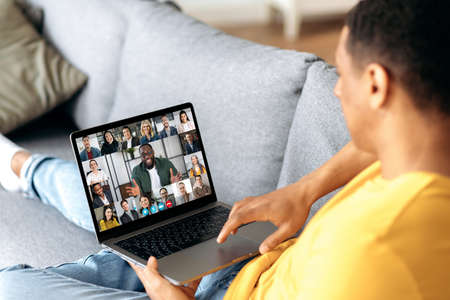 Online video communication. The guy sits on the couch in the living room, uses a laptop to...