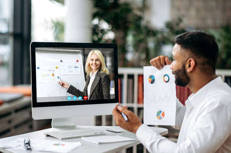 Financial online briefing. Concentrated top manager or business owner sitting at desk in office,...