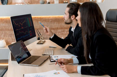 Successful, purposeful, business colleagues, traders, sit at a desktop in front of a computer...