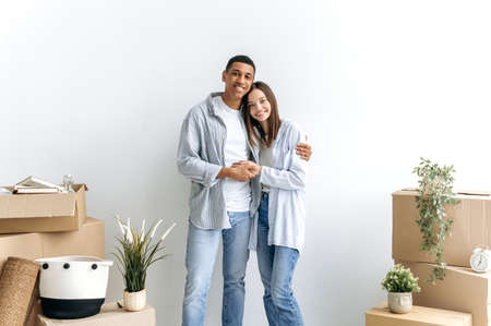 Stylish a guy and a girl in love hugging each other, multiracial excited couple standing near a...