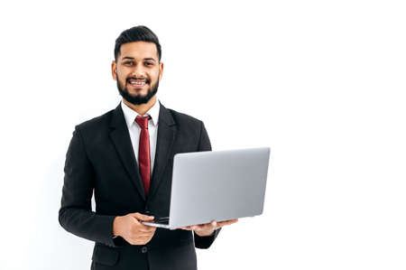 Successful handsome indian or arabian man in business suit, male entrepreneur, holding open laptop...