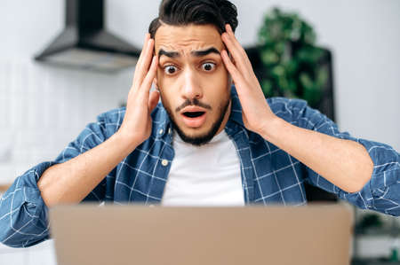 Shocked confused puzzled indian or arabian guy, freelancer or student, looking disappointment at the...