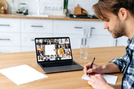 Online education. Side view of a smart caucasian male student and group of multiracial people on a...