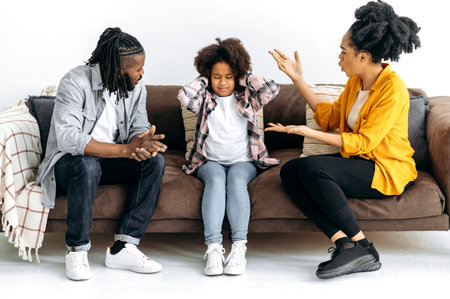 Difficulties in the relationship of parents with the child, conflict. African American parents sort things out with their preschool daughter, yell at her, the child covered her ears, ignores. Abuseの写真素材