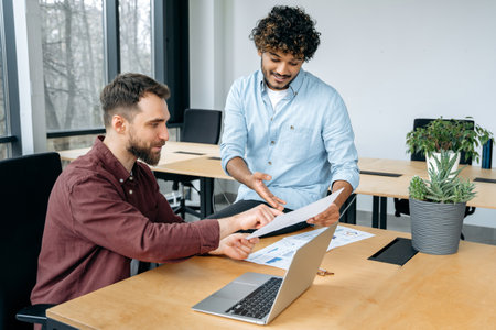 Two confident stylish male business colleagues of different ethnicity, brainstorming, working...