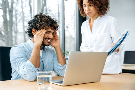 Multiracial man and woman, company colleagues, work together in the modern office, a woman came to a...