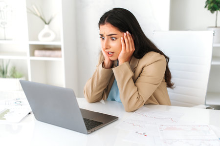 Stress, worried. Shocked indian or arabian business woman, sitting at a work desk in the office,...