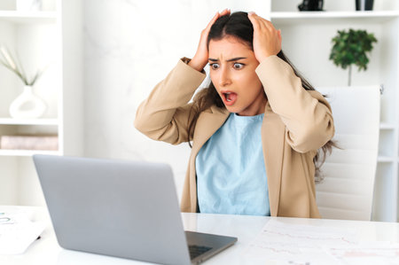Shocked indian or arabian business woman, company manager, sitting at a work desk in the office,...