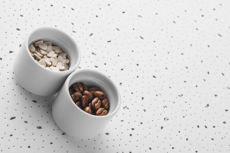 Set of saucers filled with coffee beans and sweet candy on white backgroundの写真素材