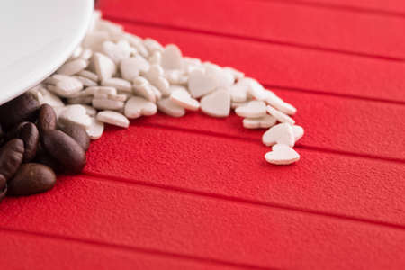 Close up view cup of coffee with coffee beans and candy assortment on white backgroundの写真素材