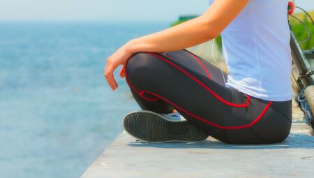 Girl sitting at seaside and relaxing, woman fitness, healthy lifestyleの写真素材