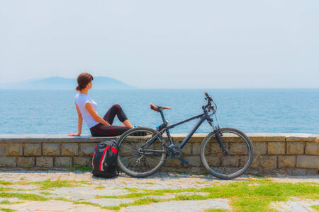 Cycling - Biker girl sitting at seaside, woman fitness, healthy lifestyleの写真素材