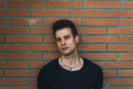 Stylish casual serious man lean back brick wall.の写真素材