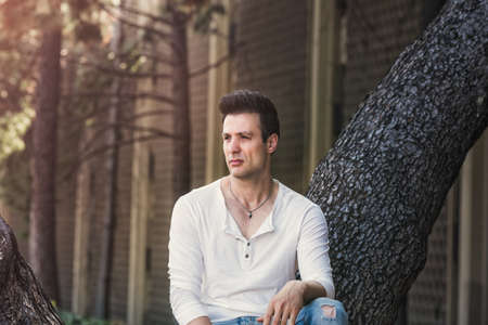 Handsome casual man sitting on tree.の写真素材