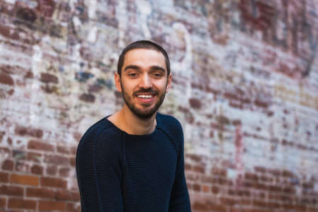 Handsome smiling and casual young man sitting on bench. High resolution photo.