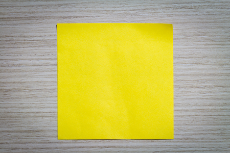 Yellow sticky note attach to a wooden wall