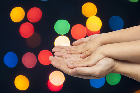 father and son holding hands on multicolored christmas lights backgroundの写真素材