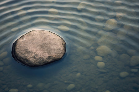 Large round stone in a rocky creek surrounded by water top view. Generative AI.の素材