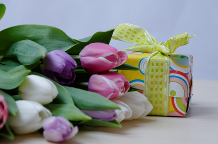 Photo background with tulips and wrapped a present on table with gray backgroundの写真素材
