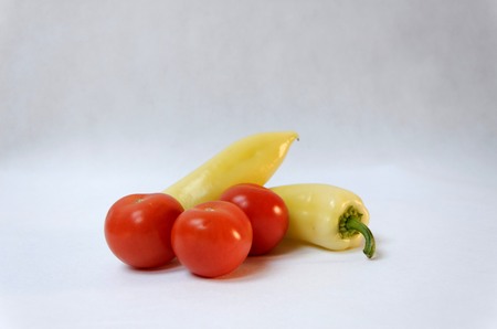 Photo Image of two yellow peppers and three red tomatoes on grey backgroundの写真素材