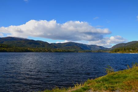 Beauty Norway nature scene with blue clear lake, hills and big cloud