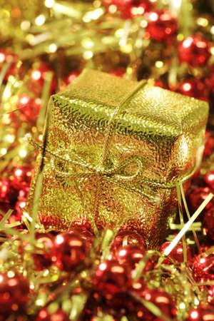 Close up of christmas present in golden wrapping with string bow on golden and red backgroundの写真素材