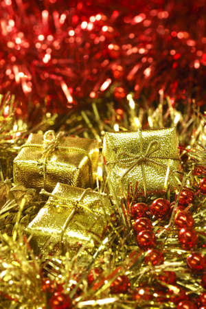 Arrangement of Christmas sparkling decorations in red and golden colours including gift boxes chain beads and tinselの写真素材