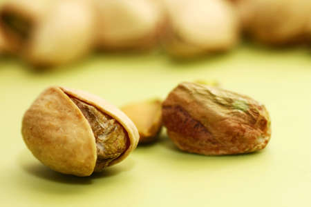Close-up of pistachio nut in open shell on green background with more pistachios blurred in foregroundの写真素材