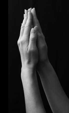 Close up of female hands folded for prayer isolated on black backgroundの写真素材