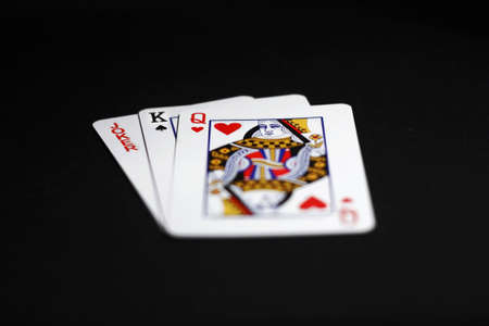 Three playing cards: joker king and queen isolated on black backgroundのeditorial素材