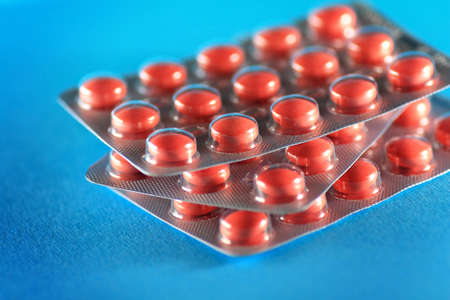 Pink tablets in plastic clear package on blue backgroundの写真素材