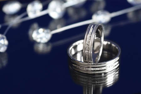 Pair of white gold wedding rings with diamonds on dark background
